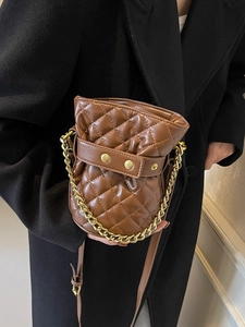 Brown quilted bucket bag with gold chain strap shown on black coat for a high-end look