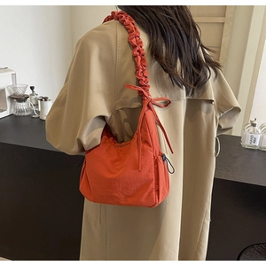 Detail van de oranje tas met trekkoorden, strikken en een geplooide schouderband