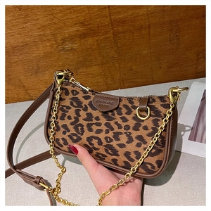 Detail shot of leopard print handbag with golden chain and dark brown leather trim