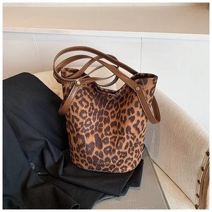 Detail of leopard print bucket bag with brown leather straps on a textile chair
