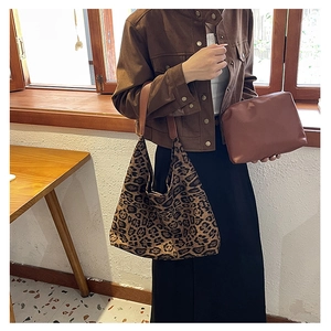 Detail of leopard print tote bag with brown leather strap and matching small pouch