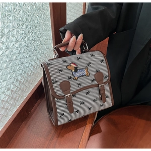 Detail of retro houndstooth backpack with cartoon dachshund embroidery and leather trim