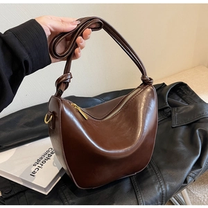 Detail of a dark coffee crescent bag featuring knotted straps and polished finish