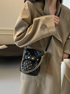 Elegant quilted bucket bag in black faux leather with gold chain strap on a model