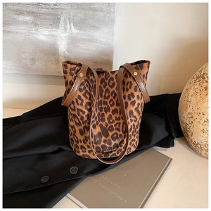 Detailed view of leopard print bucket bag with brown leather straps on a dark coat