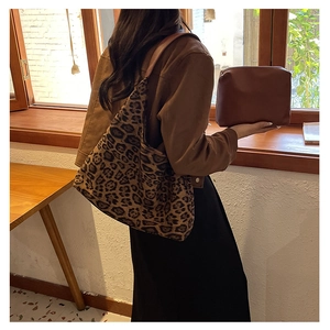 Close-up of leopard print tote bag and brown leather clutch pouch set on a model