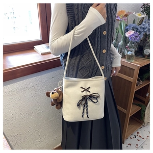 Detail of white canvas shoulder bag with brown ribbon bow and cute puppy plush charm