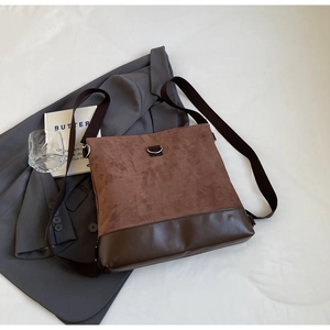 Detail of mixed textures featuring brown suede and dark polished leather on a stylish crossbody bag