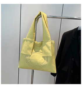 Detail of yellow pleated leather tote bag with unique circular stitching and wide strap