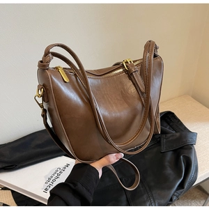 Detail view of brown faux leather texture and gold zipper on a chic bucket bag