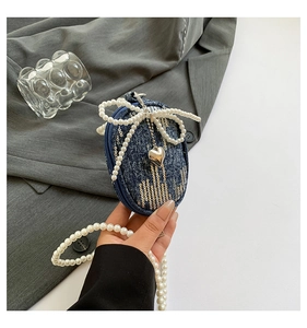 Détail du mini sac en denim bleu avec paillettes dorées, pendentif cœur et perles
