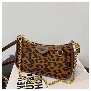 Detail of leopard print underarm bag with gold hardware and leather shoulder strap