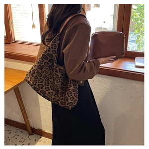 Detail of leopard print tote bag with brown zipper pouch in a cozy lifestyle setting