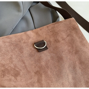 Detailed close-up of brown suede fabric with dark webbing strap and silver D-ring buckle