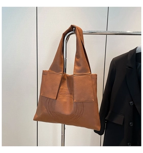 Close-up of brown PU leather tote bag with circular stitching and wide shoulder strap
