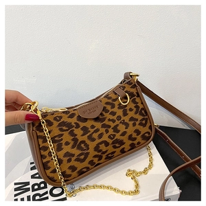 Close-up of leopard print baguette bag with golden chain strap and leather edge detail
