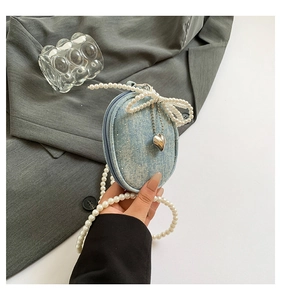 Gros plan d'un mini sac en denim avec nœud en perles et charmant pendentif en cœur
