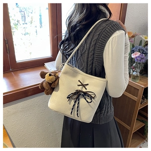 Detail of off-white canvas shoulder bag with brown bow lace and cute bear charm