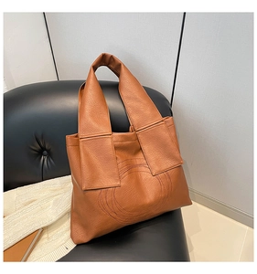 Detail of brown lychee grain tote bag featuring unique circular stitching on the leather