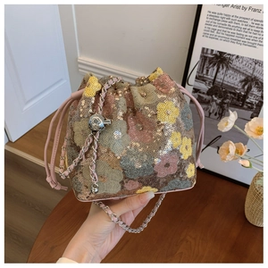 Dettaglio borsa a secchiello con paillettes floreali, coulisse e sfera in metallo dorato