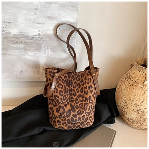 Close-up of leopard print suede bucket bag with leather strap on black coat background
