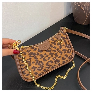 Detail of leopard print handbag with brown leather trim and golden metal chain strap