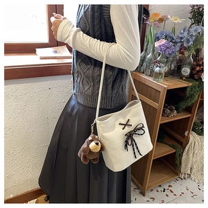 Close-up of beige canvas bag with dark brown cross-lacing and a cute plush puppy charm