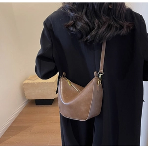 Brown matte leather crescent bag shown on model with vintage minimalist styling