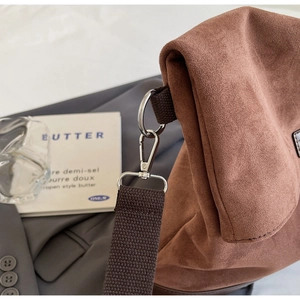 Detailed close-up of brown suede tote bag featuring silver metal ring and fabric strap