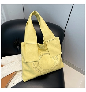 Close-up of yellow tote bag showing litchi grain texture and circular stitching details