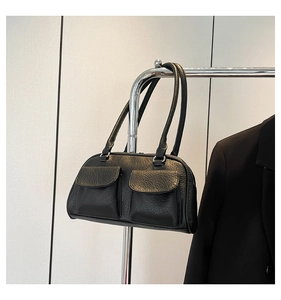 Detail view of black lychee grain leather underarm bag with double front flap pockets