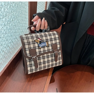 Close-up of retro plaid bag with embroidered dachshund and double buckle closure