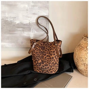 Detail shot of leopard print bucket bag with leather handles and gold metal rivets