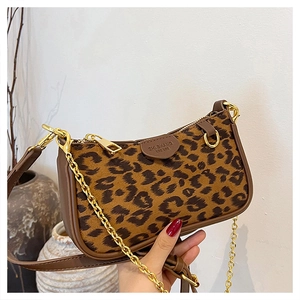 Close-up of leopard print faux fur texture with dark brown leather trim and gold chain detail