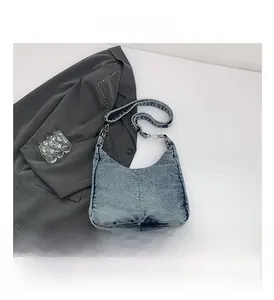 Detail view of light blue denim shoulder bag with vertical stitching and silver buckles