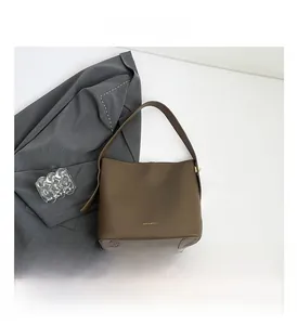 Detail view of coffee brown leather bucket bag featuring bottom studs and golden logo