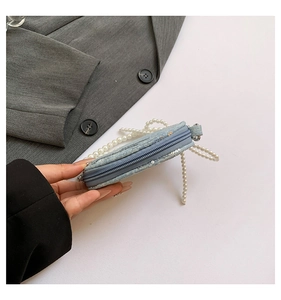 Détail du mini sac bleu clair à paillettes avec une bandoulière décorative en perles nacrées