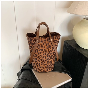 Close-up of leopard print bucket bag with brown leather handles and gold metal rivets