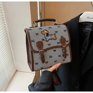Close-up of retro houndstooth handbag with cartoon dog embroidery and brown leather trim