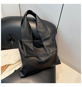Close-up of black PU leather tote bag featuring orange spiral ring embroidery details