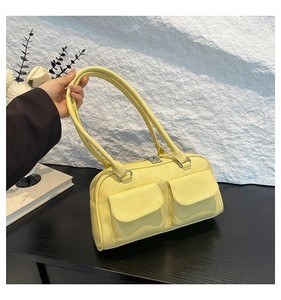 Detail of a bright yellow shoulder bag with twin flap pockets and textured faux leather