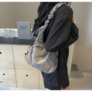 Detailweergave van een grijze cloud bag met trekkoordbandjes en een geplooide nylon structuur