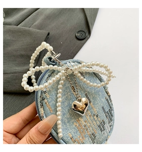 Détail du porte-monnaie rond en denim avec paillettes, nœud perle et bandoulière