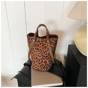 Detail of leopard print velvet bucket bag with brown leather handles and spacious interior
