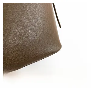 Close-up detail showing the premium lychee pattern leather texture on a brown bucket bag