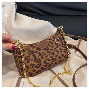 Macro detail of leopard print shoulder bag with brown leather trim and golden chain strap