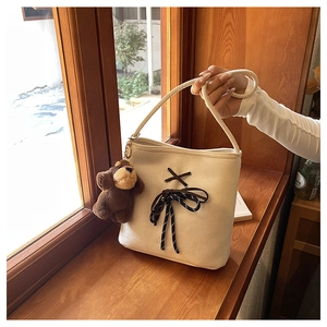 Close-up of beige canvas bucket bag with brown criss-cross ties and cute dog charm detail