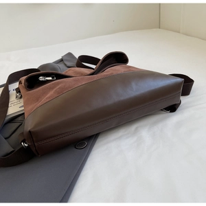 Detail of retro dark brown PU leather and suede patchwork tote bag on white bedding