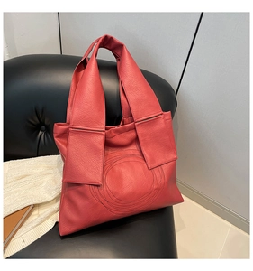 Close-up of red tote bag featuring litchi texture and geometric stitched patterns