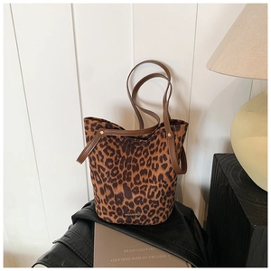 Close-up of leopard print suede bucket bag on black leather jacket with vintage decor